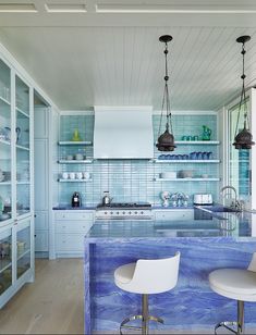 a kitchen with blue marble counter tops and white chairs in front of an island that has two bar stools next to it