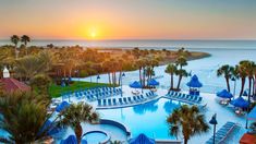 an aerial view of the pool and beach at sunset