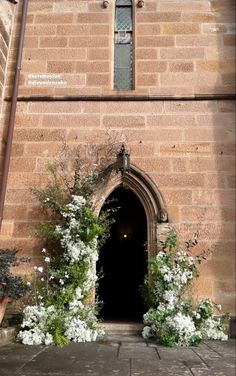 the entrance to an old brick building with white flowers