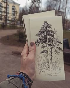 a person holding up an open book with trees on it