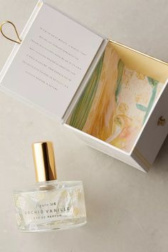 an open box containing a perfume and a card with a gold cap on the top