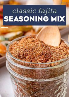 a glass jar filled with seasoning next to a wooden spoon