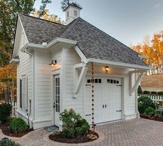 a white house with a black roof and brick walkway leading to the front door area