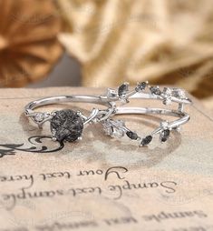 two silver rings with black and white stones on top of an old book, sitting on a table