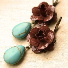 two flower shaped earrings with turquoise and brown flowers hanging from the earwires on a beige background