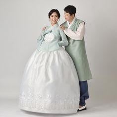 a man and woman dressed in traditional korean wedding attire posing for a photo together on a white background