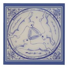 a blue and white plate with three rabbits on it's side, in the center