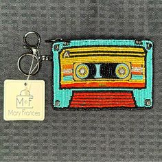 a keychain with a beaded cassette design on it and a tag attached to it