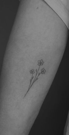 a small flower tattoo on the left inner forearm and arm, with tiny flowers growing out of it