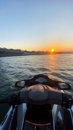 the sun is setting over the water as seen from a boat on the water with it's front end in the foreground