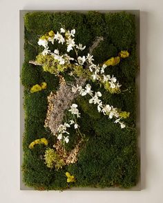 a moss covered wall with white flowers on it