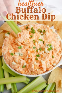 a white bowl filled with buffalo chicken dip surrounded by celery and tortilla chips