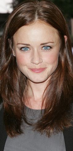 a close up of a person with long hair and blue eyes wearing a gray shirt