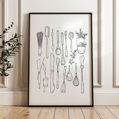 a black and white framed art print with kitchen utensils on the wall next to a potted plant