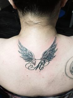 the back of a woman's neck with an angel tattoo on it