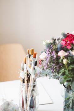 two vases filled with flowers and brushes on a table