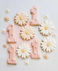 decorated cookies in the shape of numbers and flowers on a white tablecloth with pink icing