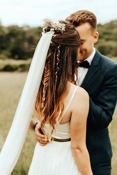 a bride and groom standing in a field