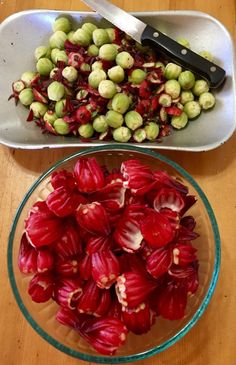 there are two bowls with red flowers in them next to a knife and bowl of green sprouts