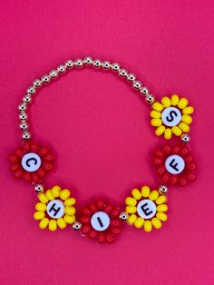 a beaded bracelet with letters and flowers is shown on a pink background, as if it were made from legos