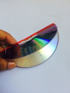 a person holding a compact disc in their left hand and the other hand is touching it