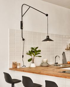 a kitchen counter with three chairs and a potted plant on the bar top next to it