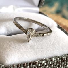 an engagement ring sitting on top of a white cloth in a woven basket next to a pillow