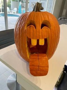 a carved pumpkin with its mouth open and tongue out, sitting on top of a counter