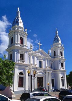 a white church with two steeples and cars parked in front