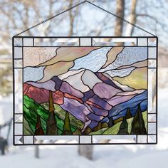 a stained glass window hanging from the side of a house with snow on the ground