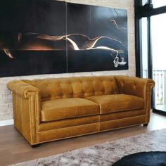 a tan leather couch sitting in front of a large painting