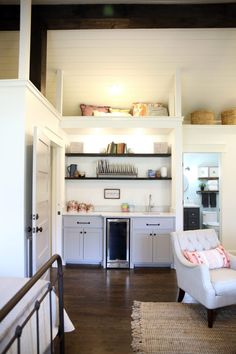 a white chair sitting in the middle of a room next to a kitchen and dining area