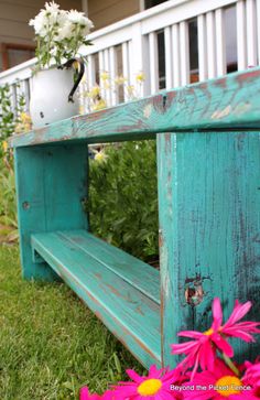 a wooden bench sitting on top of a lush green grass covered field next to flowers