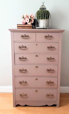 a pink dresser with flowers and a birdcage on top