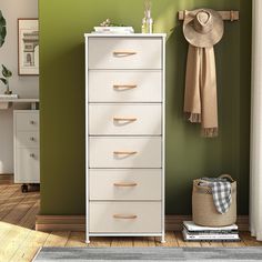 a white dresser sitting next to a green wall