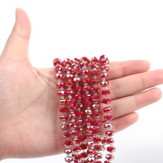 a hand holding some red beads on it's palm and the beading is shiny