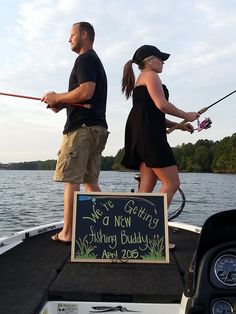 a man and woman fishing on a boat with a sign that says we're getting a new fishing buddy