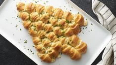 a white plate topped with cheesy bread on top of a black table next to a striped towel