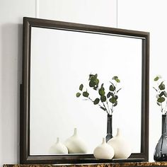 three vases with flowers in them are on a mantle next to a large mirror