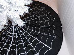 a black and white spider web umbrella next to a christmas tree