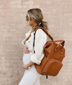 a pregnant woman carrying a brown purse