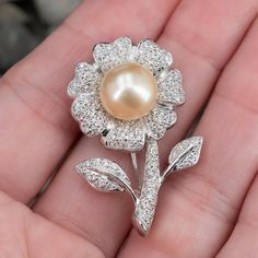 This beautiful floral brooch contains one (1) cultured south sea pearl that is post-set in the center of the flower. The rest of the flower is pavé set with a total of one-hundred sixteen (116) round brilliant cut diamonds. The brooch measures 36.6mm long by 23.9mm wide and 11.6mm thick and has a hinged straight pin finished with a trumpet clasp. Luxury White Flower Brooches, Golden South Sea Pearls, Straight Pins, Floral Brooch, Sea Pearl, South Seas, Sea Pearls, South Sea Pearls, Pearl Flower