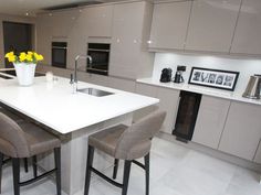 a kitchen with white counter tops and gray chairs