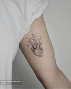 a heart tattoo with flowers on the left side of the arm and in the middle