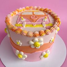 a pink and yellow cake with flowers on it sitting on a white plate against a pink background