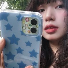 a woman holding up a phone case with stars on it