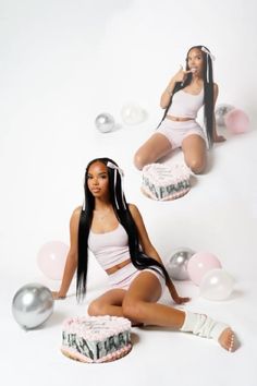 a woman sitting on the ground with two cakes and balloons in front of her,