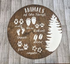 a wooden sign with animal footprints and words on it that says animals at the forest