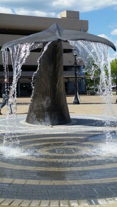 a fountain with water spouting from it's sides in front of a building