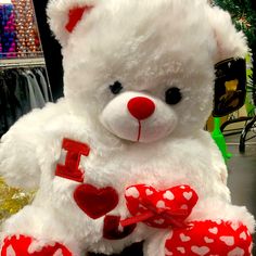 a white teddy bear with red hearts on it's chest